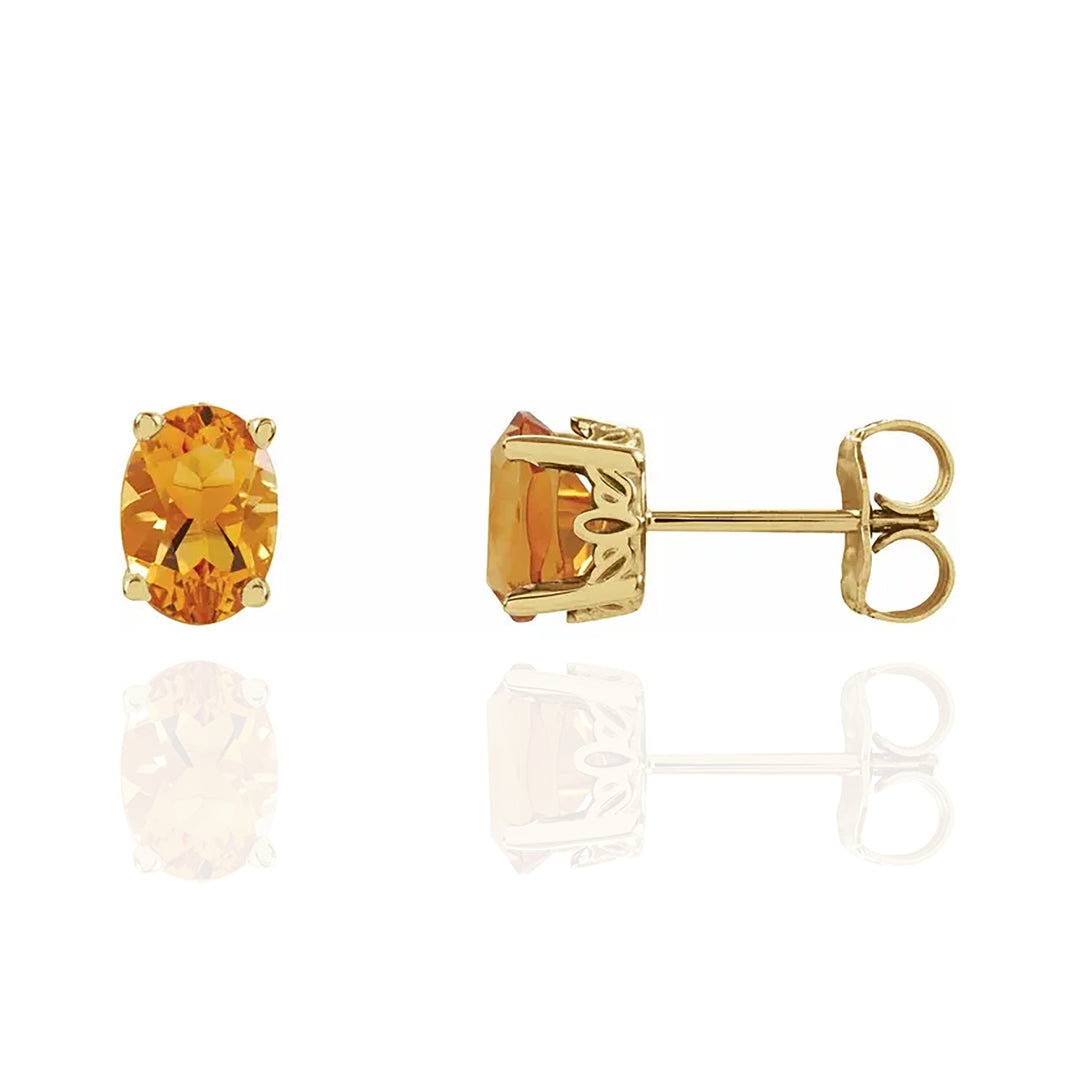 Gold earrings with citrine gemstones on a white background