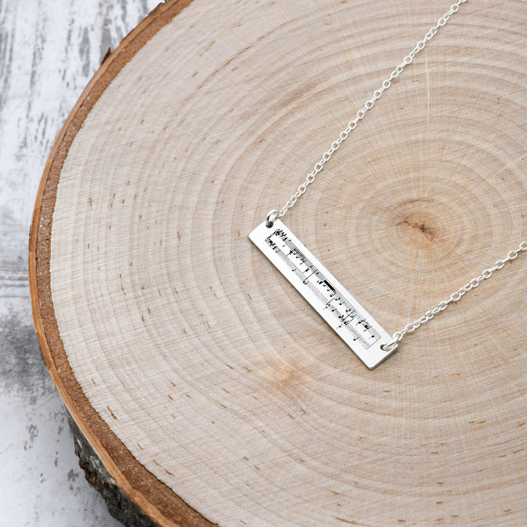Silver necklace with a bar pendant on a wooden surface