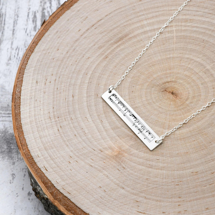 Silver necklace with a bar pendant on a wooden surface