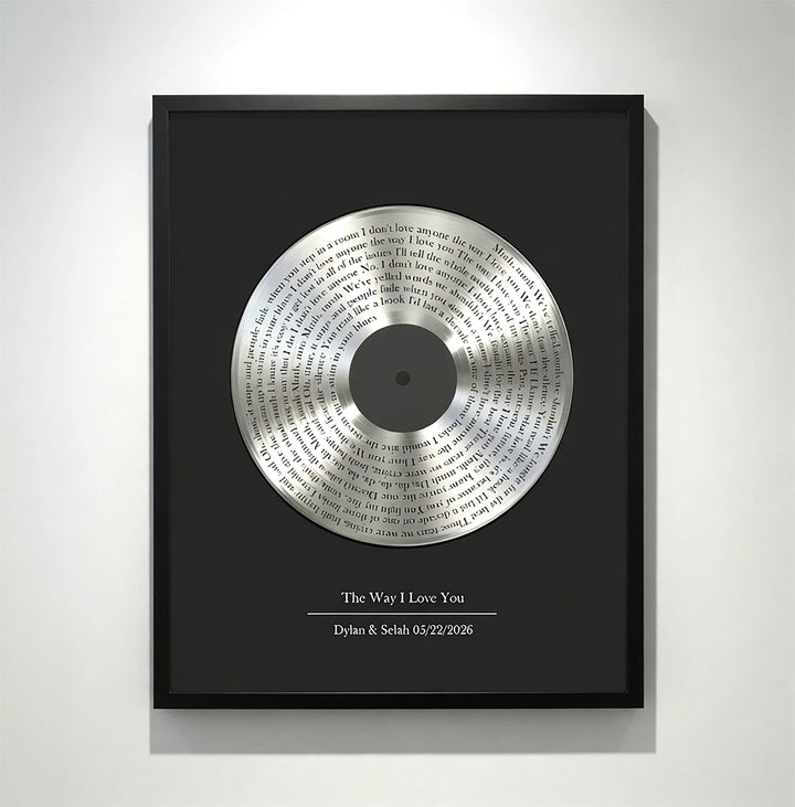 Framed vinyl record with engraved text on a white wall
